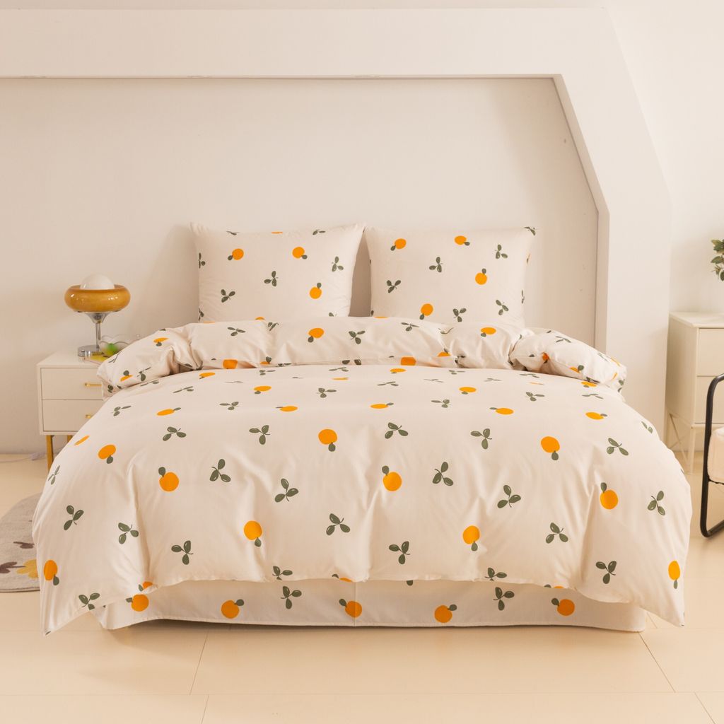 A neatly made bed with a duvet cover and pillows featuring a fruit print.