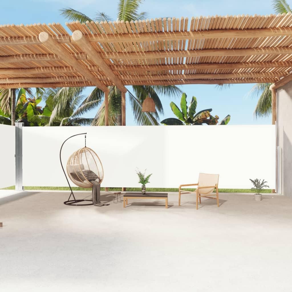 An outdoor patio area with a retractable side awning, furniture, and tropical plants.