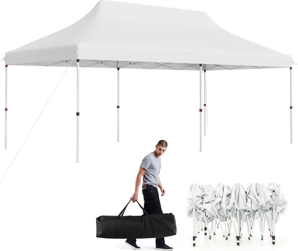 A man carries a folded tent bag next to a set-up tent.