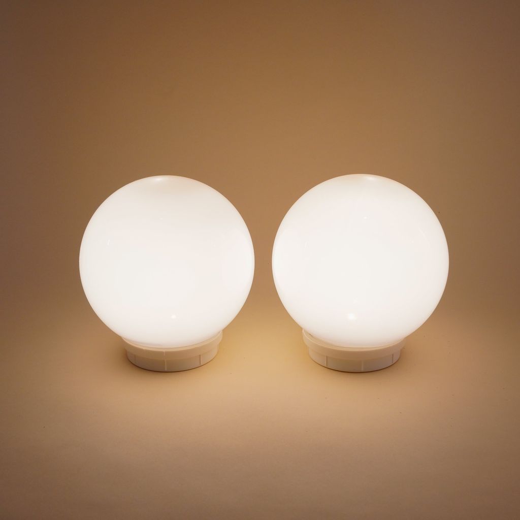 Two white spherical solar lights are shown on a light brown background.