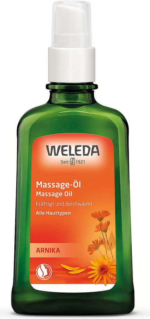 A green glass bottle of Weleda Arnika Massage Oil with an orange label.