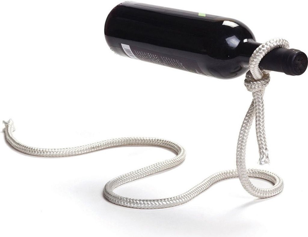 A black wine bottle is suspended horizontally by a thick white rope tied in a knot around its neck, with the rope forming a base on a white surface.