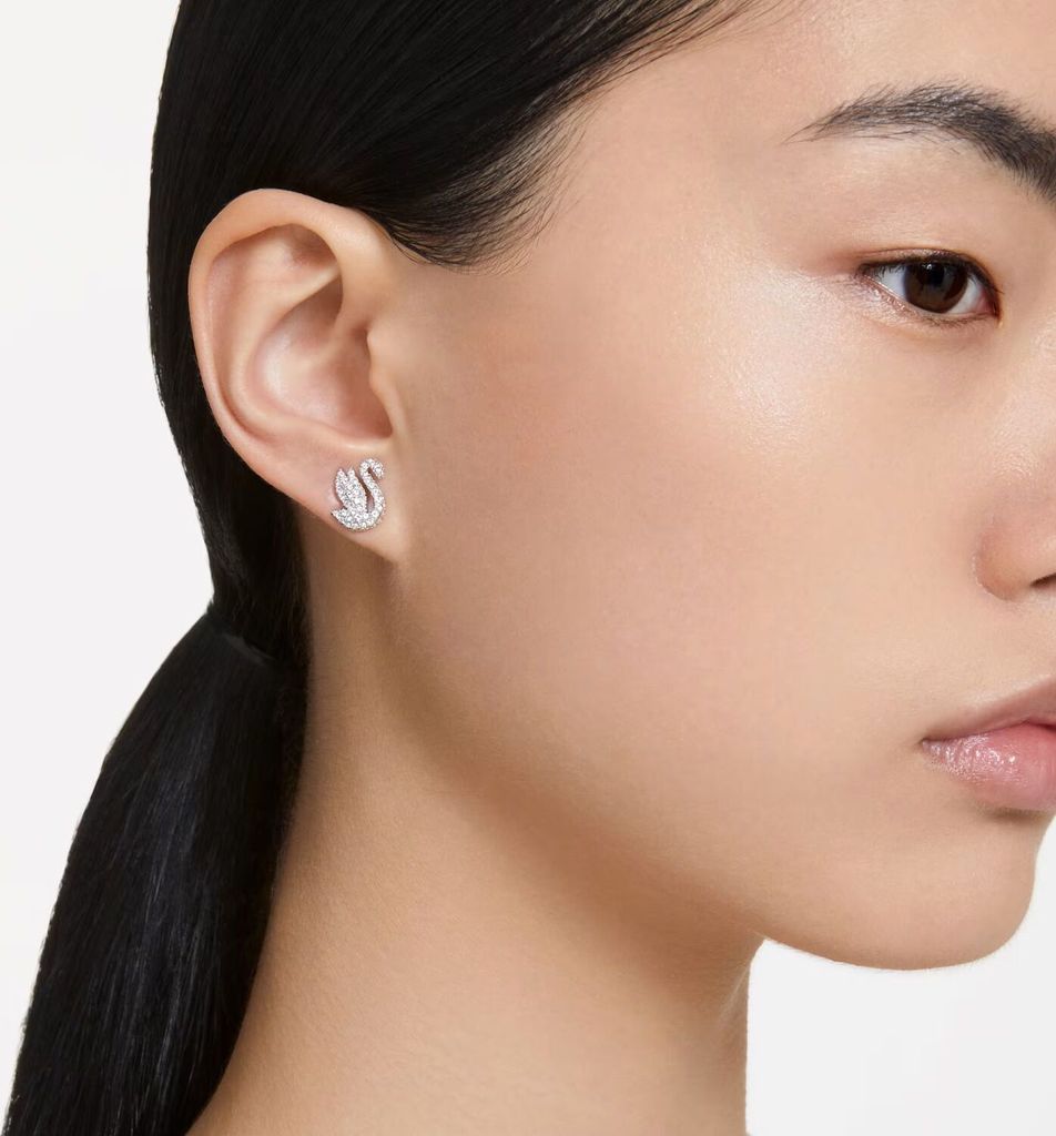 A close-up shot of a woman's ear wearing a swan-shaped earring.