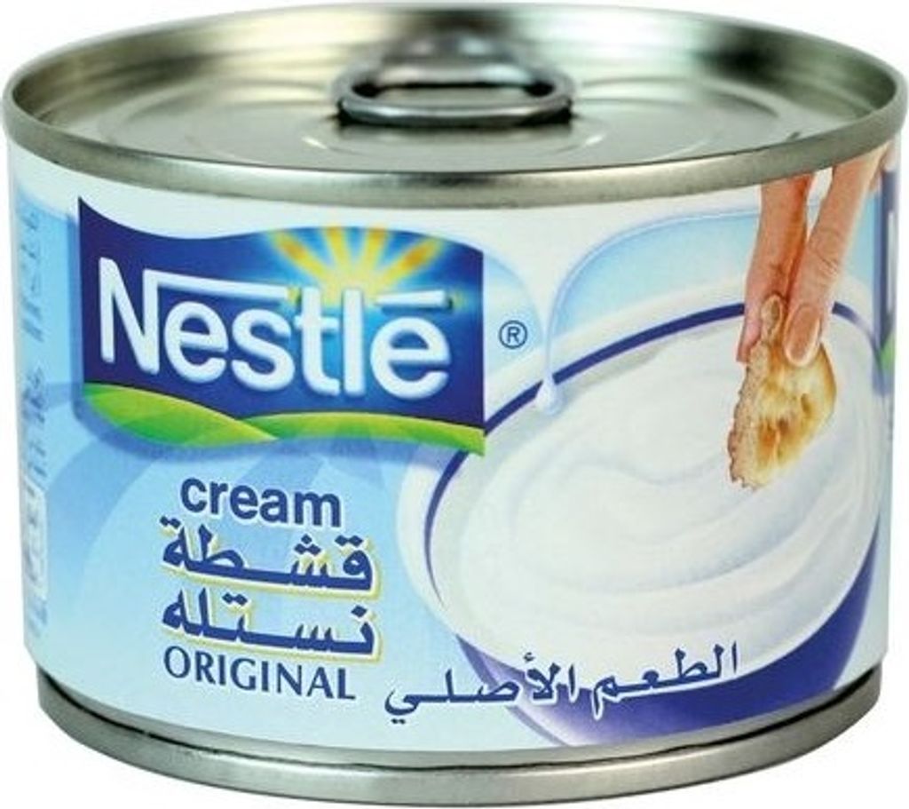 A can of Nestlé cream with a hand dipping a piece of bread into it.