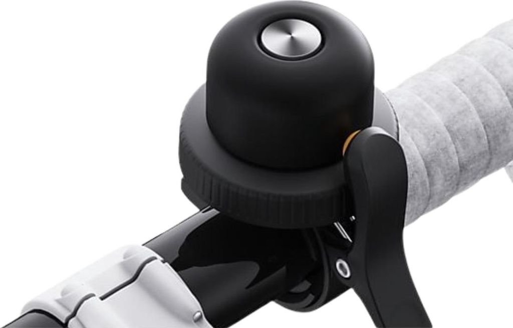 A close-up shot of a black bicycle bell mounted on a handlebar.