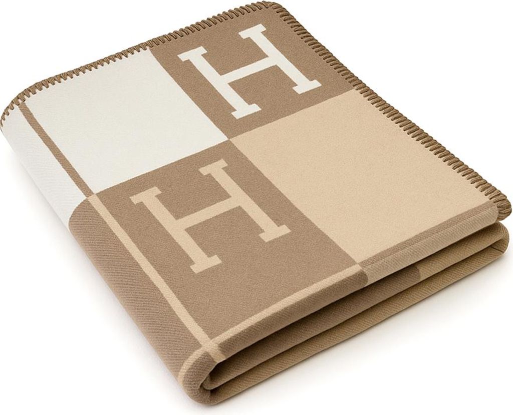 A folded blanket with a checkered pattern and the letter 'H' on it.