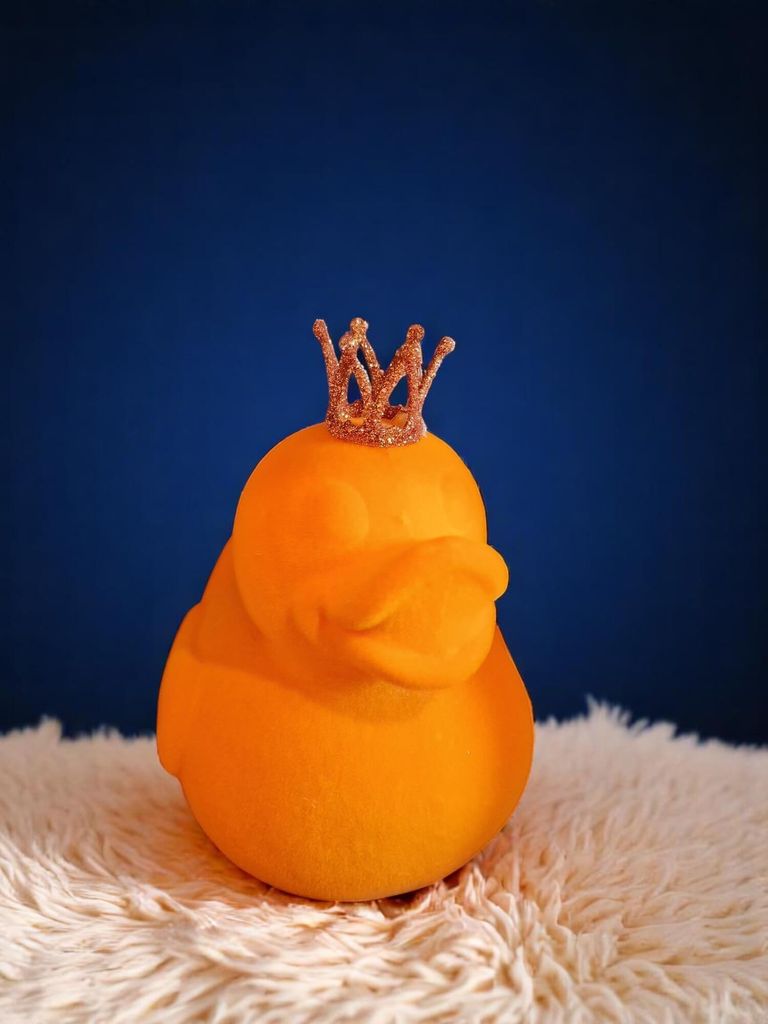 Große, beflockte Ente in Orange mit Glitzerkrone. Stilvolle Deko aus Kunststoff