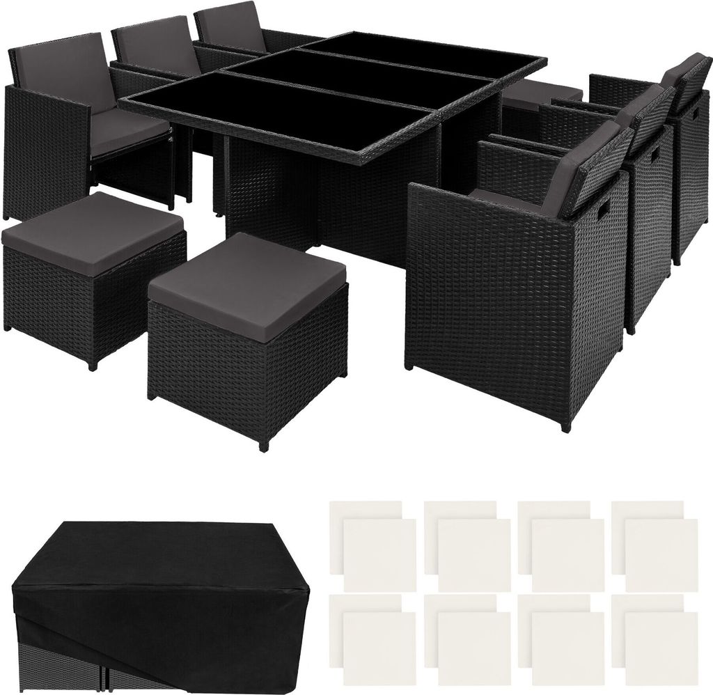 A black rattan outdoor furniture set with a glass-topped table, chairs, and ottomans, along with a black cover and white cushions.