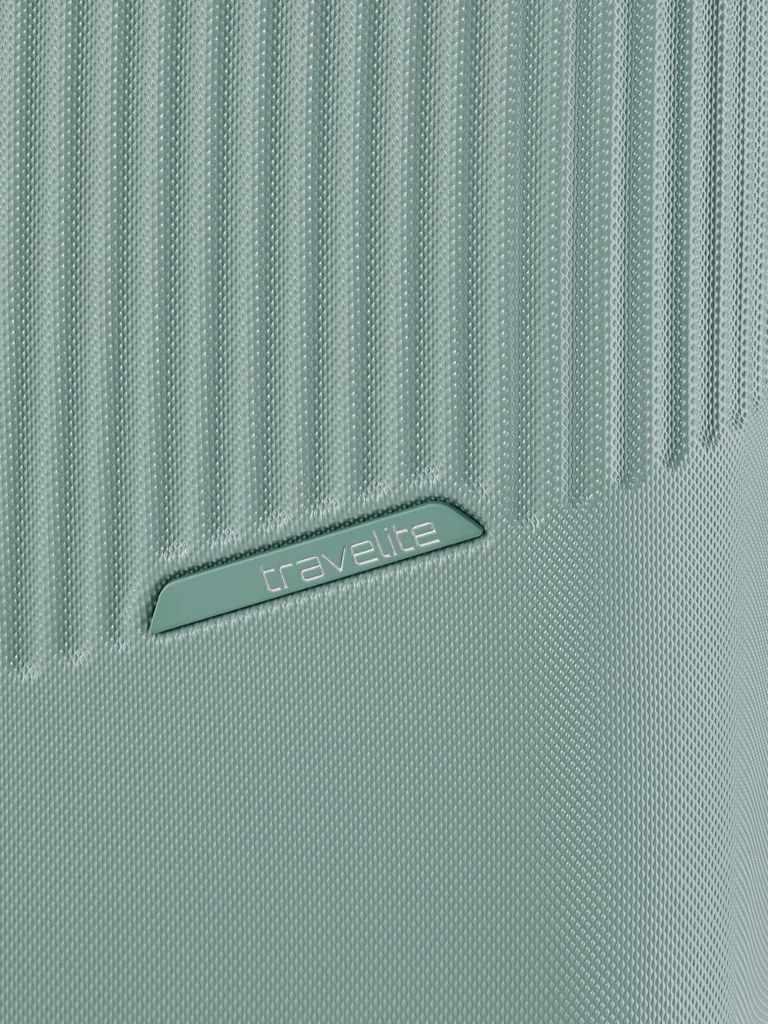 A close-up view of the textured surface of a light green suitcase, featuring the embossed 'Travelite' logo.