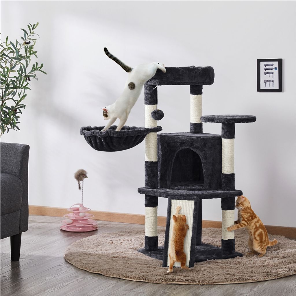 Two cats playing on a multi-level cat tree in a living room setting.