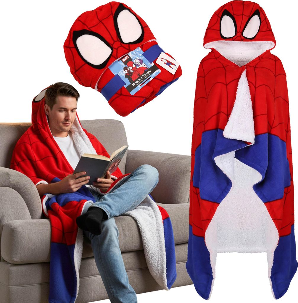 A man is sitting on a couch reading a book while wearing a Spider-Man hooded blanket.