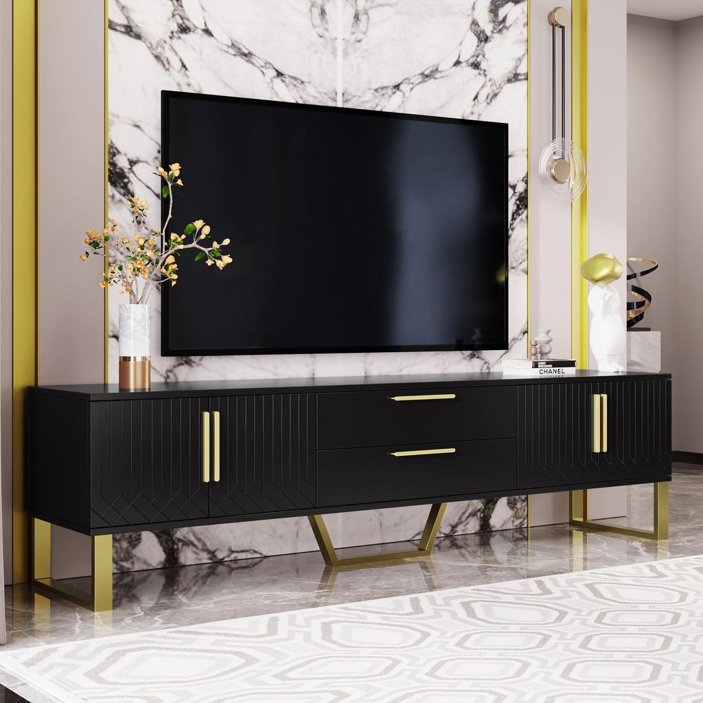 A black TV stand with gold accents and a large TV on top, set against a marble wall.