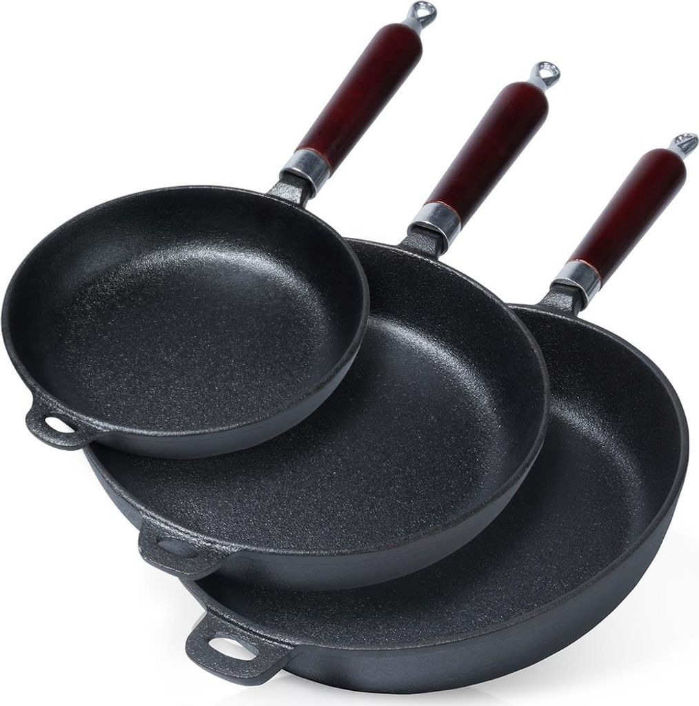 Three cast iron frying pans of different sizes are stacked on a white background.