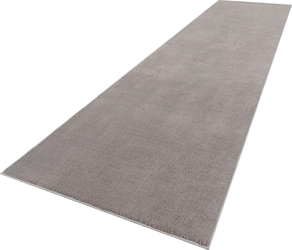 A long, gray rug is shown from a diagonal angle against a white background.