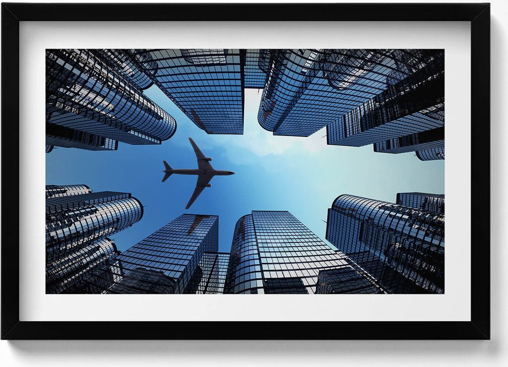 Flugzeug über Gebäuden– Wandbild mit Rahmen – Gerahmtes Bild – Wanddekoration – 60x40 cm – Schwarz Rahmen
