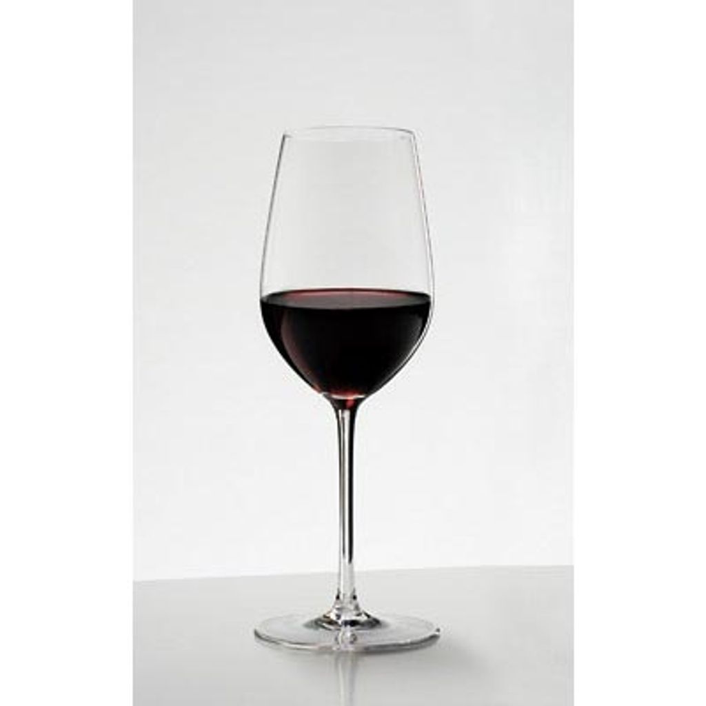 A single glass of red wine on a white surface.