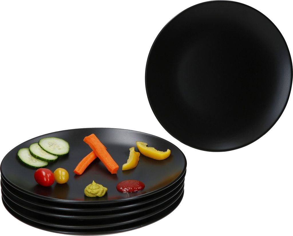 A stack of black plates with some vegetables and condiments on the top plate, and another black plate in the background.