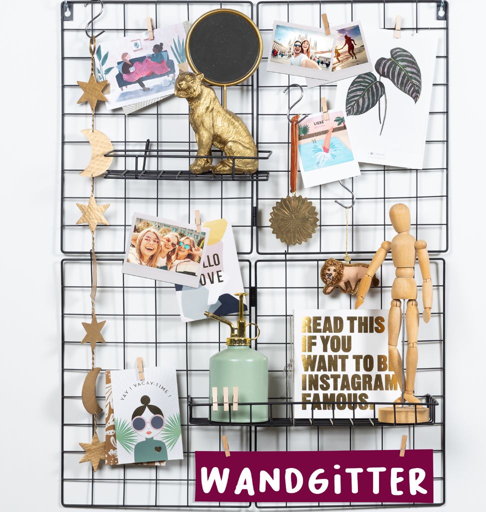 A black wire grid display board decorated with various items like photos, ornaments, and a small watering can.