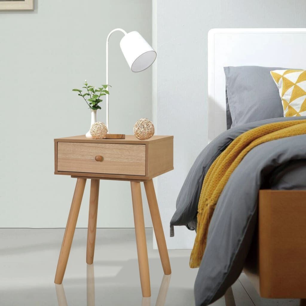 A bedside table with a lamp and decorative items next to a bed.