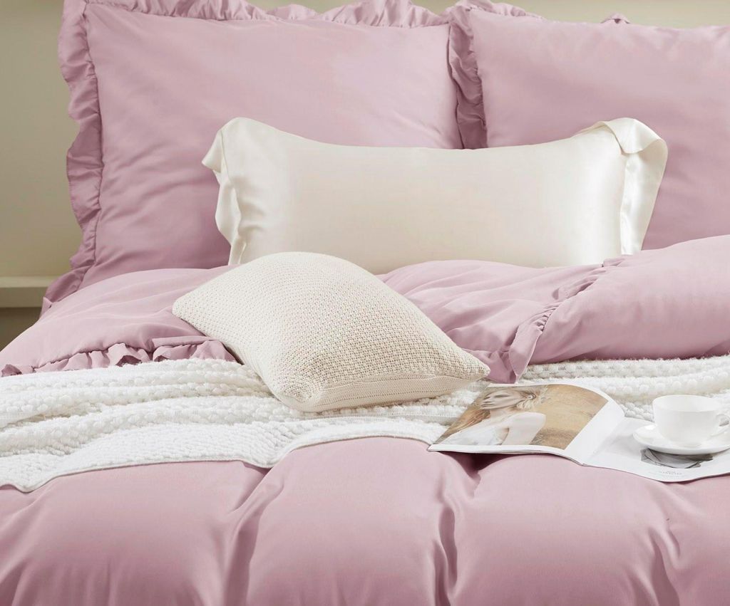 A close-up view of a neatly made bed with pink bedding and pillows.
