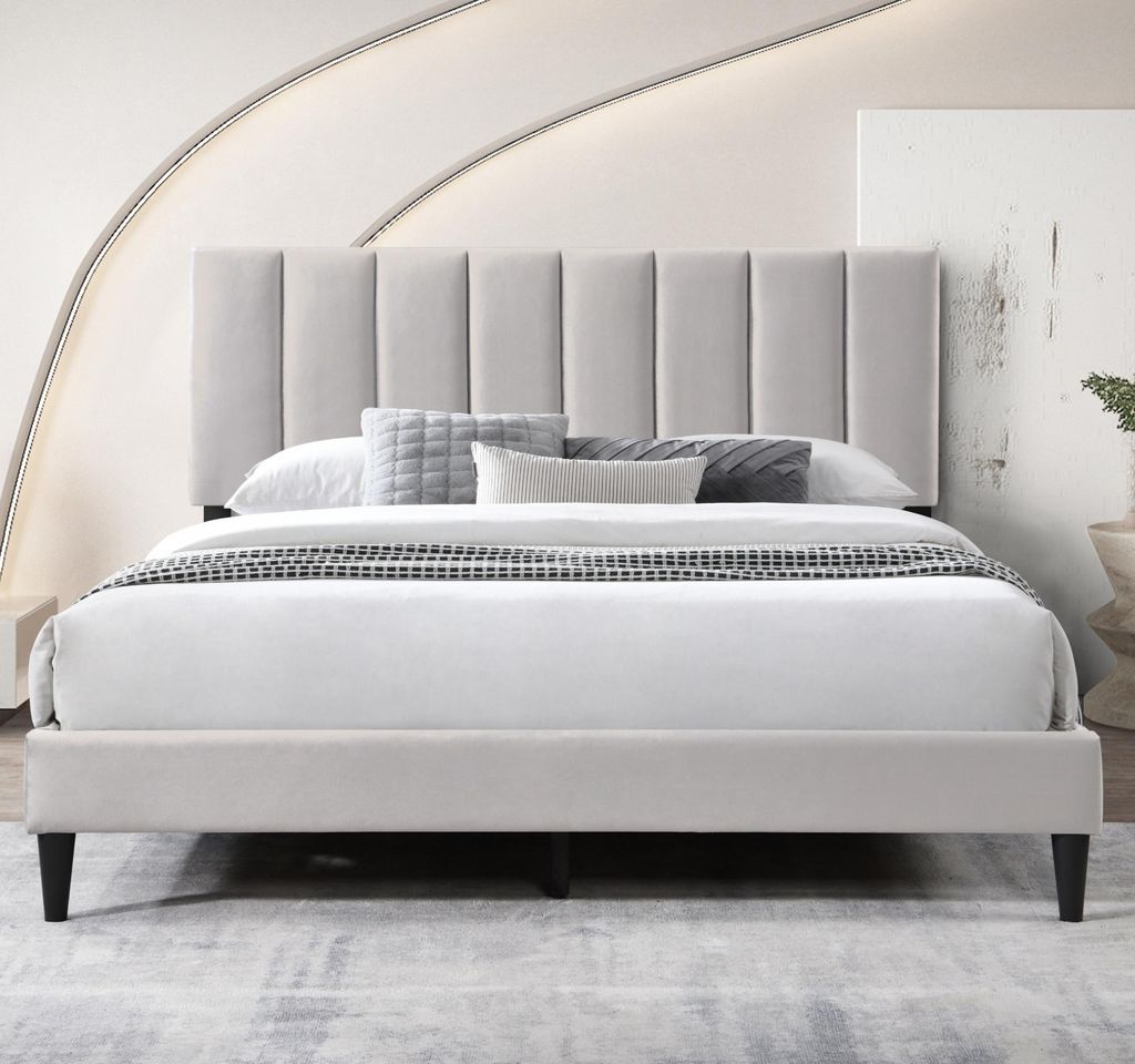 A bed with a padded headboard and bedding in a room.