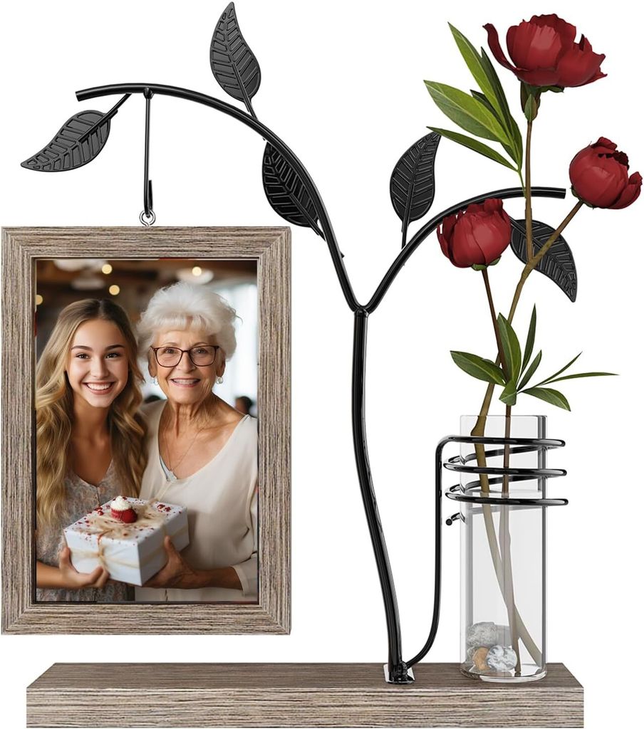 A decorative picture frame with a metal tree branch holding a photo and a glass vase with flowers.