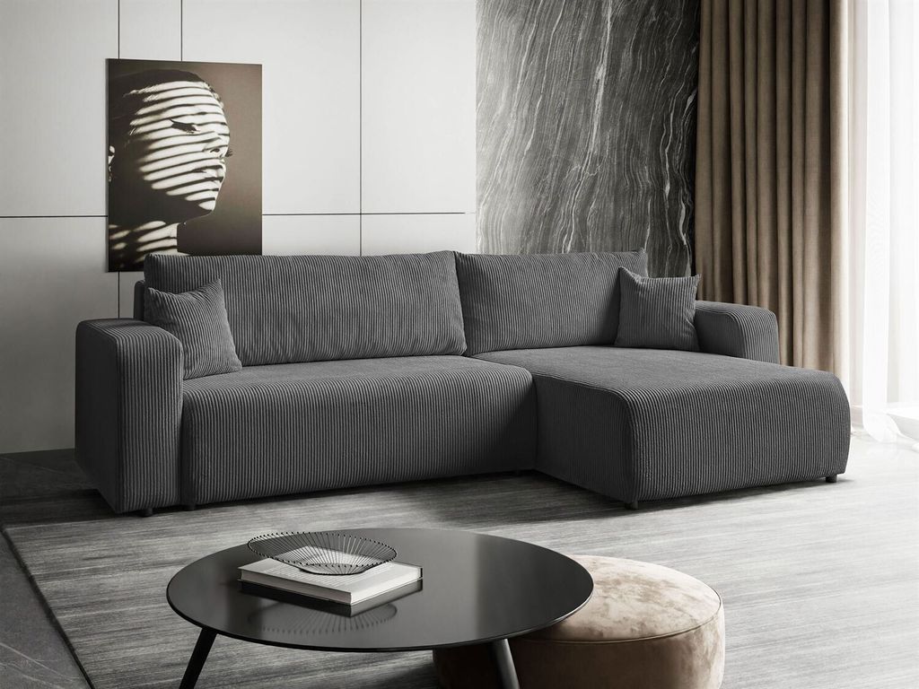 A modern living room with a gray sectional sofa, a black coffee table, and abstract art on the wall.