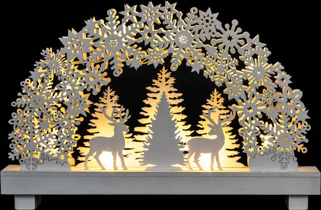 A decorative Christmas arch with snowflakes, trees, and reindeer, illuminated by warm lights.