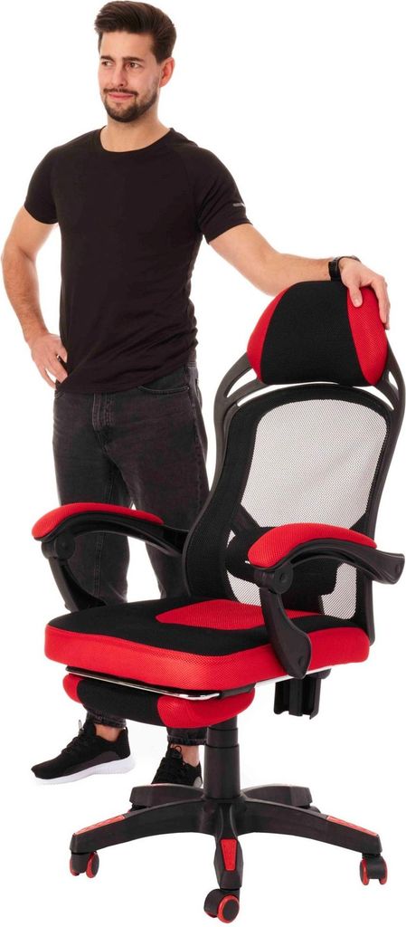 A man standing next to a red and black gaming chair.