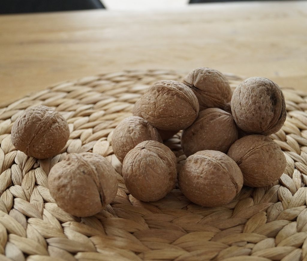 A pile of walnuts on a woven placemat.