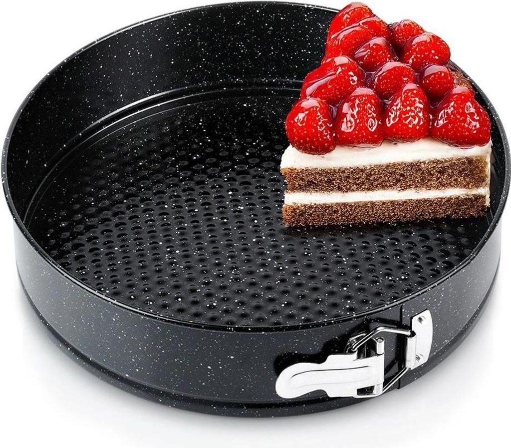 A slice of cake topped with strawberries sits inside a black springform pan.