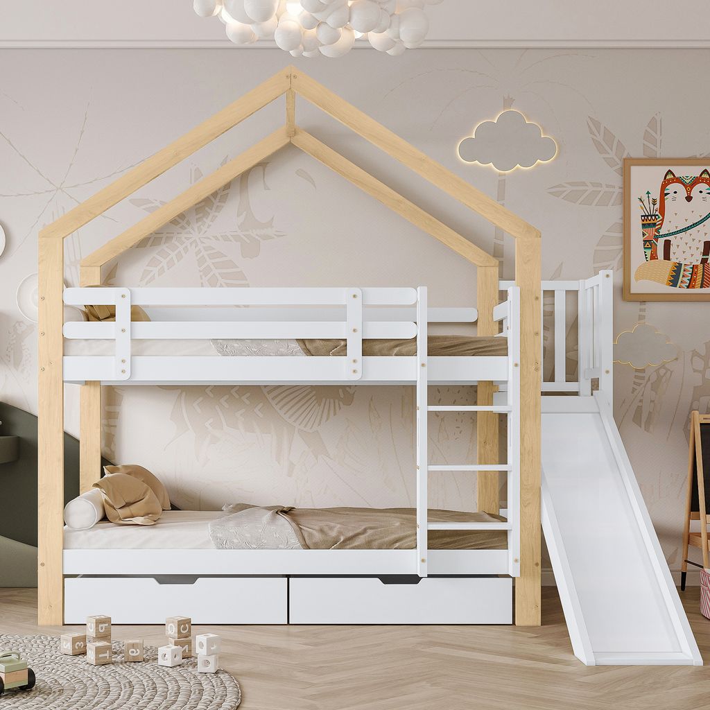 A children's bunk bed with a house-shaped frame, slide, and drawers, set in a bedroom with decorative wallpaper.
