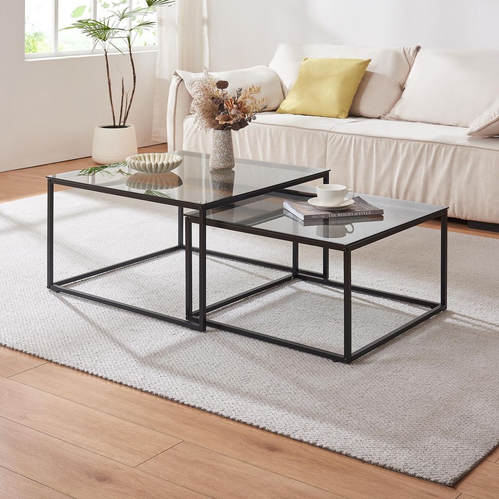 A living room scene with a sofa, coffee tables, and a plant.