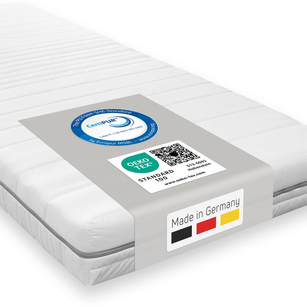 A white mattress with a grey band around it displaying certifications and country of origin.