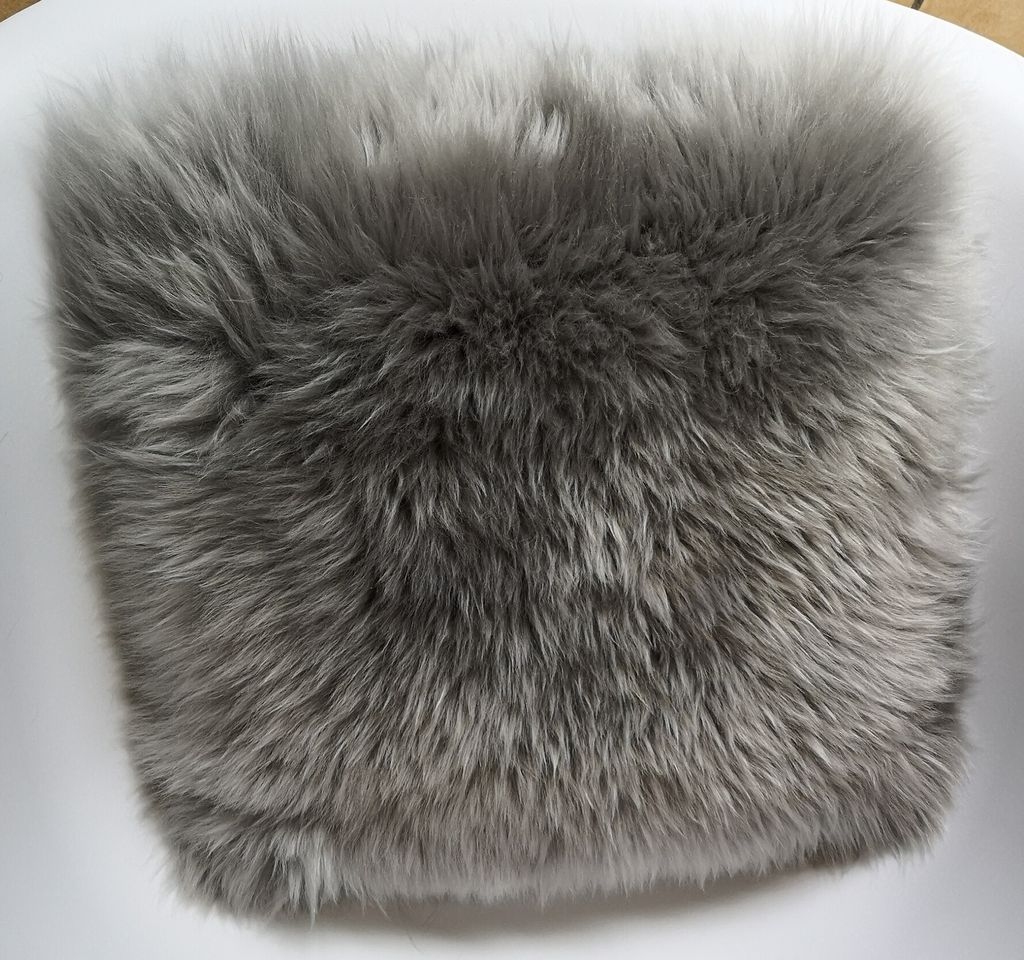 A close-up view of a gray, fluffy sheepskin seat cushion.