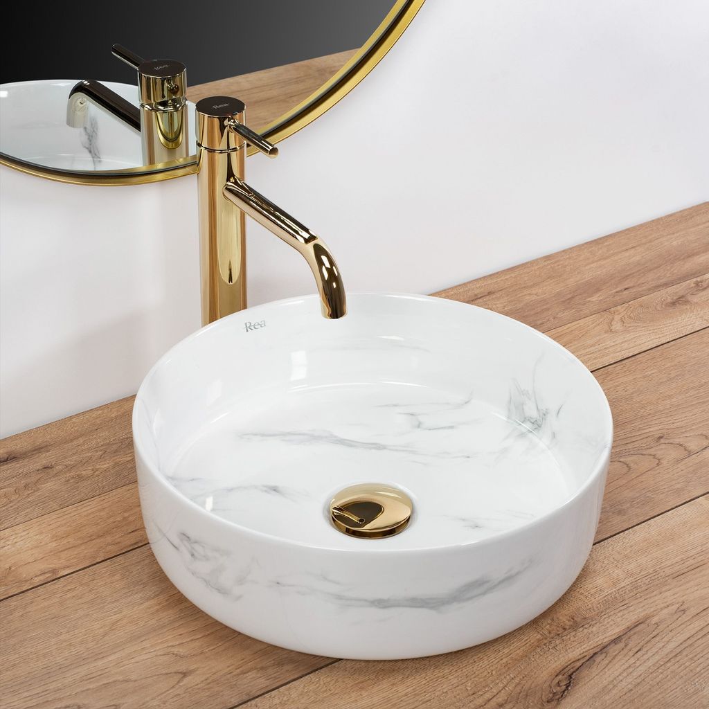 A close-up shot of a marble-patterned sink with a gold faucet.