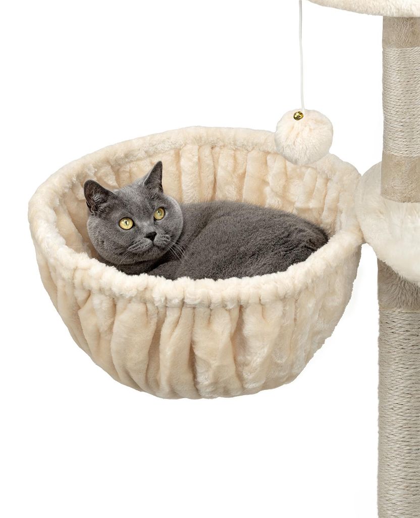 A gray cat is resting in a beige cat bed attached to a cat tree.