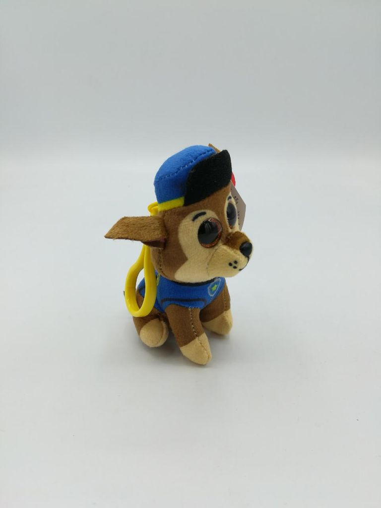 A plush toy dog wearing a blue hat and blue uniform, with a yellow loop attached to its collar.