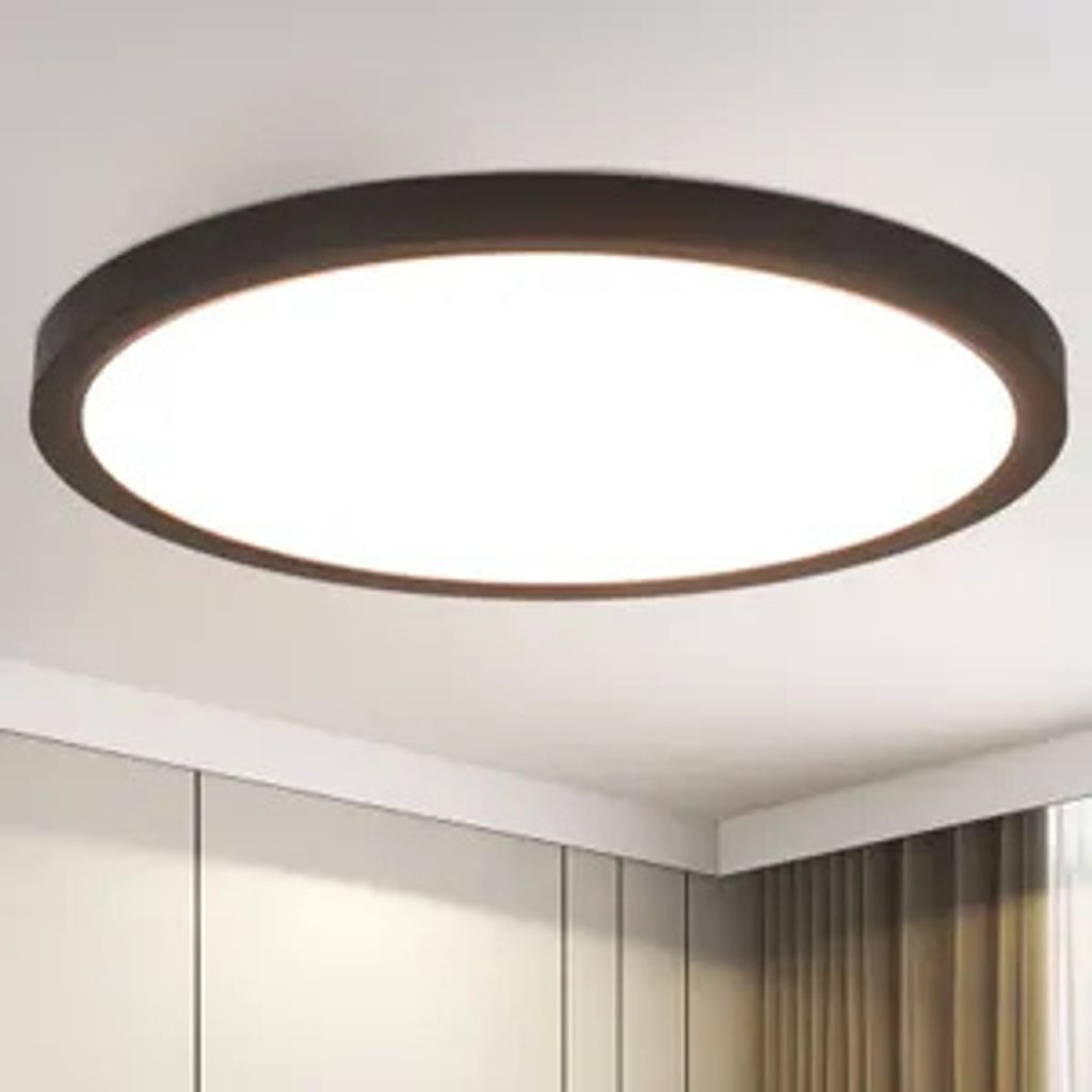 A modern, round LED ceiling light with a black frame is mounted on a white ceiling.