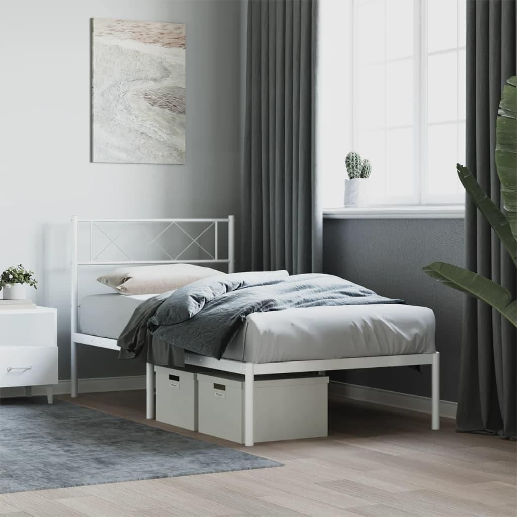 A white metal bed frame with a headboard, bedding, and storage boxes underneath, set in a bedroom with grey curtains and a painting on the wall.