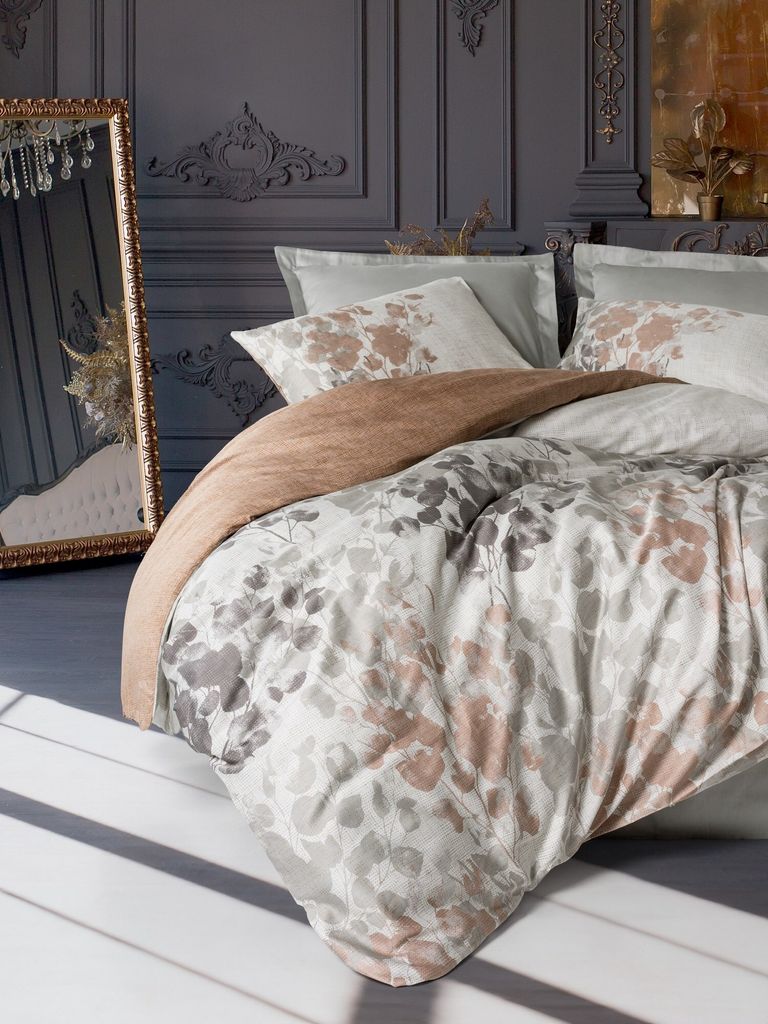 A bedroom scene with a bed dressed in bedding with a floral pattern, a mirror, and decorative wall molding.