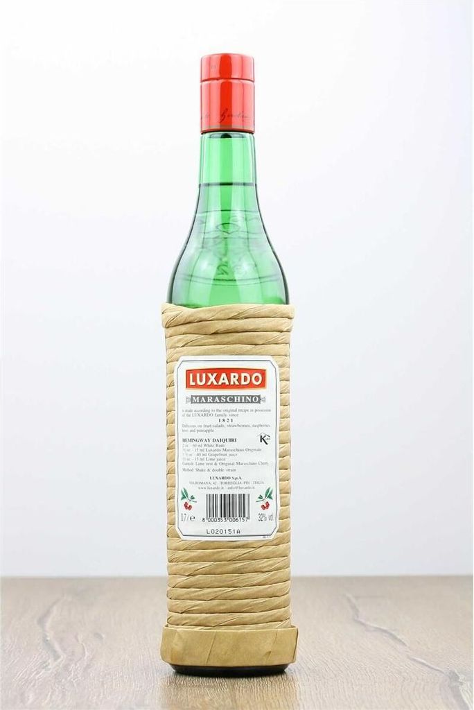 A bottle of Luxardo Maraschino liqueur on a wooden surface against a white background.