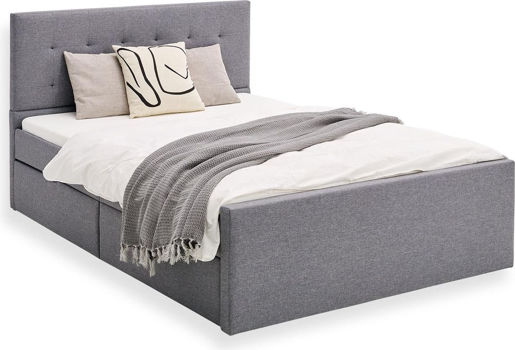 A grey upholstered bed with pillows and a blanket.