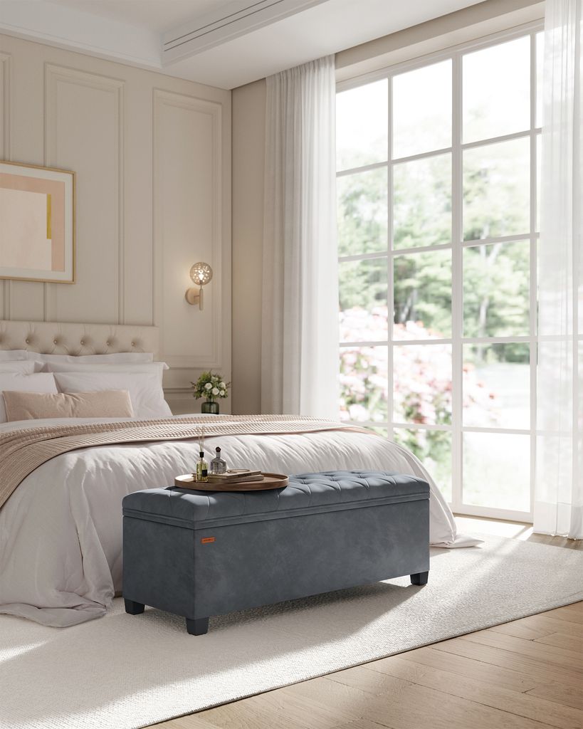 A bedroom scene with a bed and a storage bench in front of it.