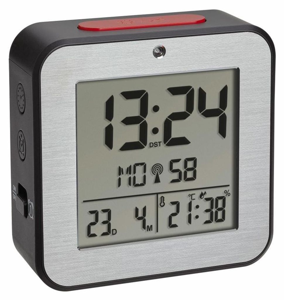 A digital alarm clock with a silver frame and a black body, displaying the time and other information on its screen.