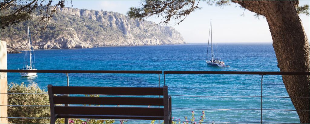 Wallario selbstklebendes Poster - Einsame Bank am Meer - Spanien im Sommer, Größe: 50 x 125 cm