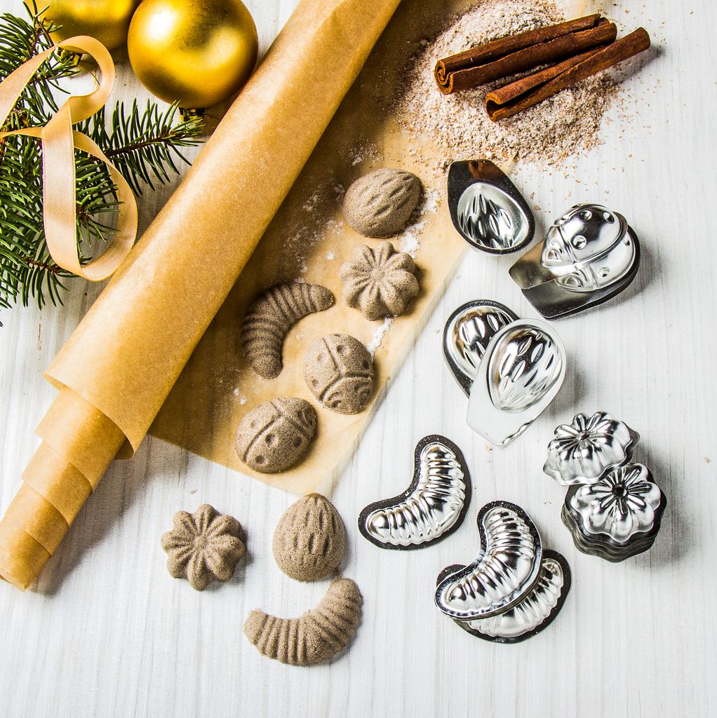 Christmas baking scene with cookie cutters, dough, cinnamon sticks, and ornaments.