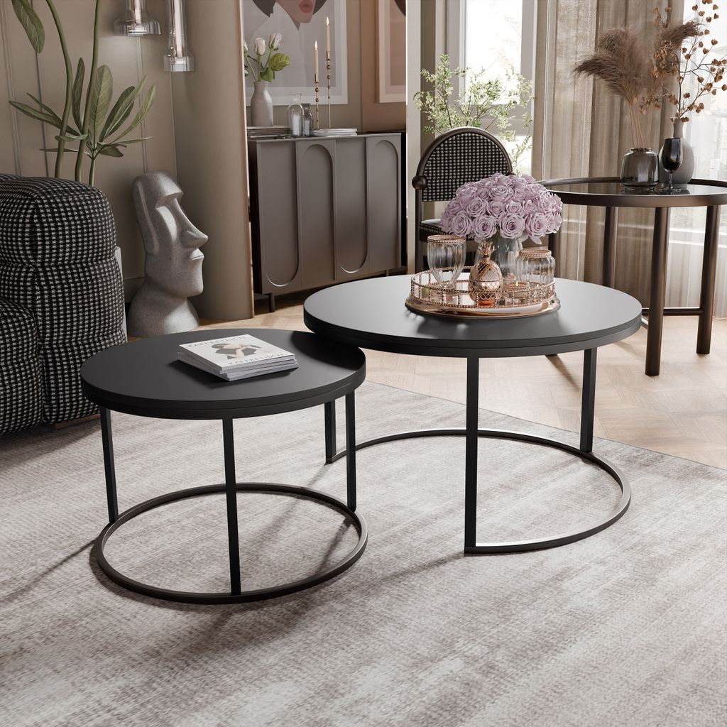 A living room scene with two round coffee tables, a decorative statue, and plants.