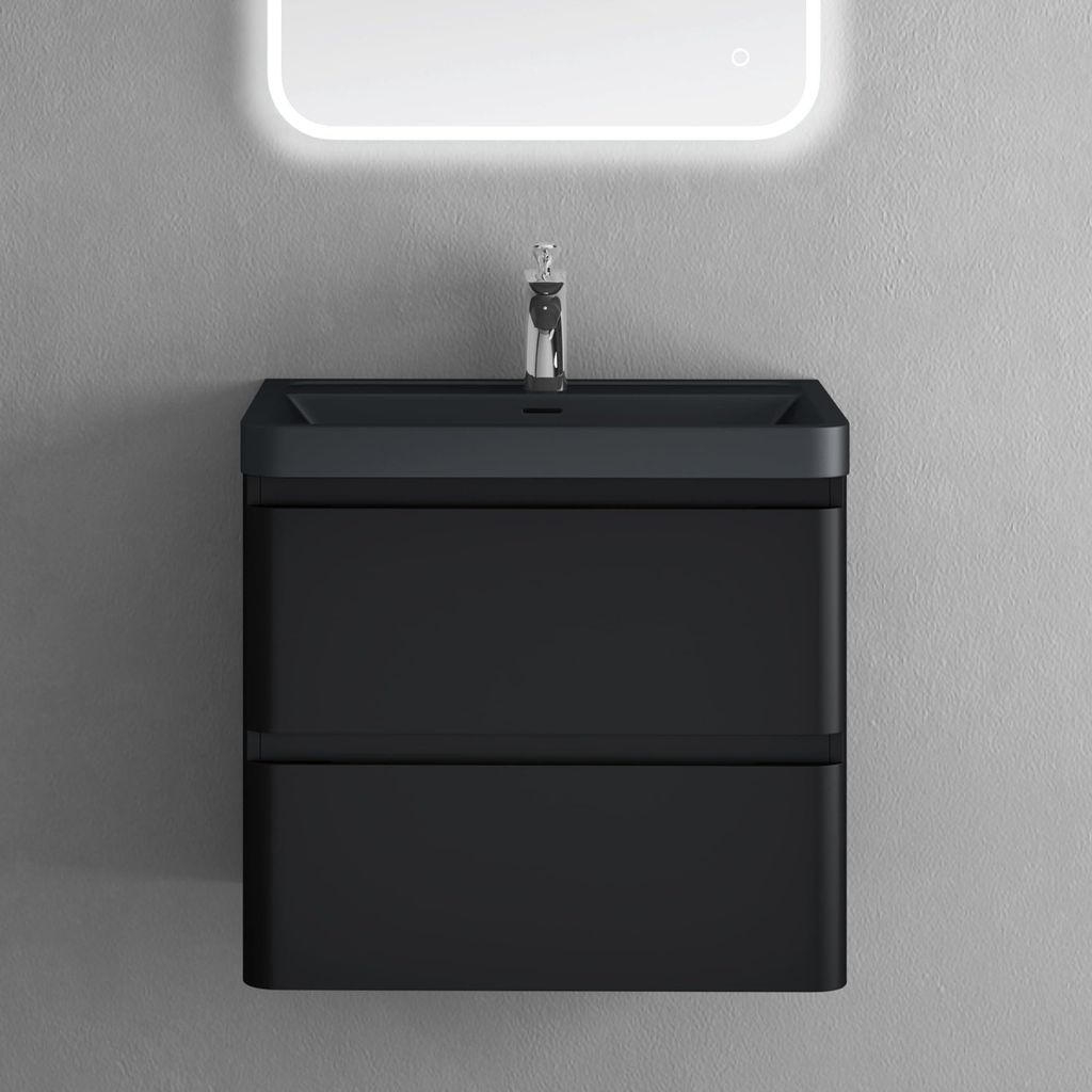 A black vanity with a sink and faucet against a gray wall, under a lighted mirror.