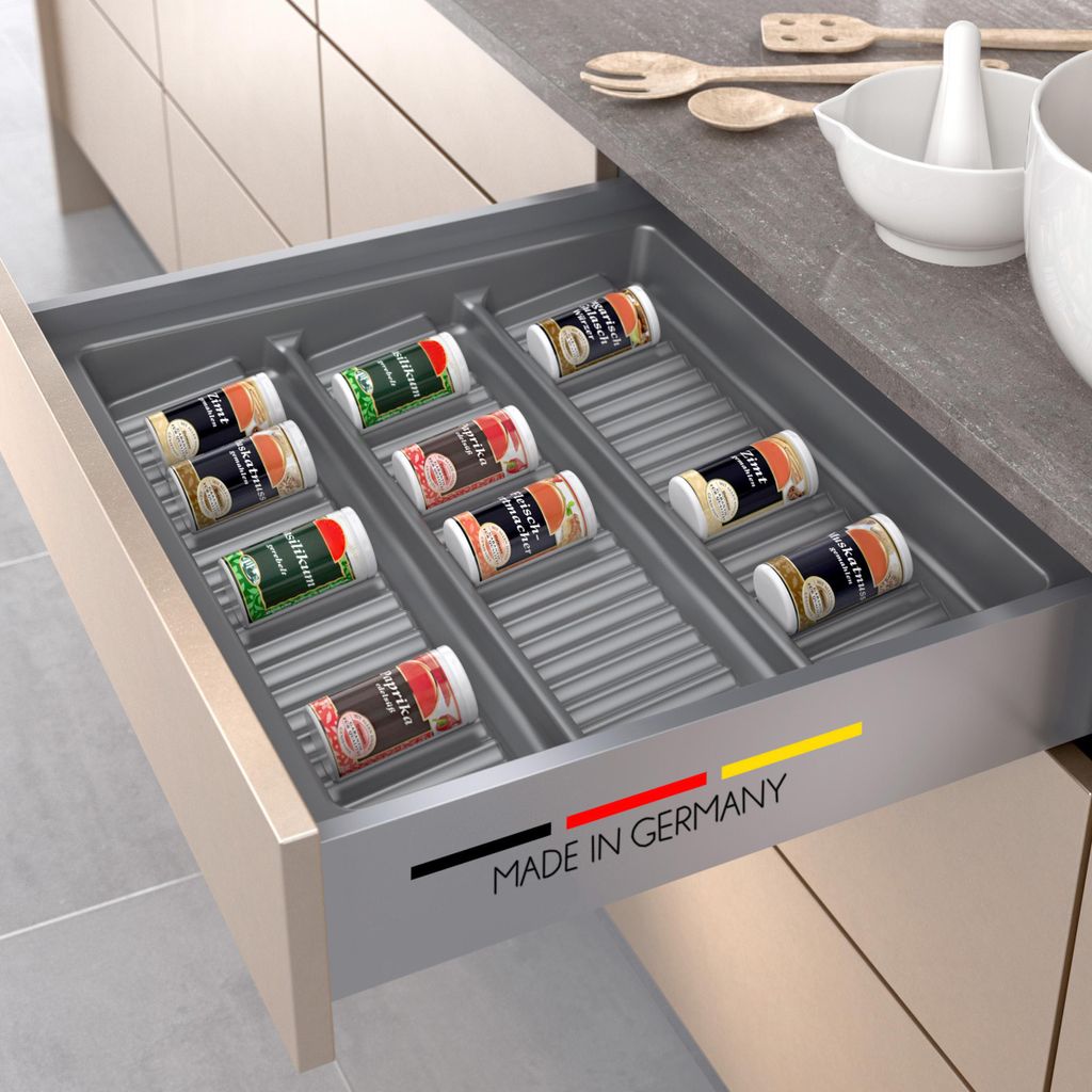 A kitchen drawer with a spice rack insert filled with spice jars.